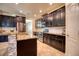 Modern kitchen with dark cabinets, stainless steel appliances, granite countertops, and tile flooring at 19082 Umberland Pl, Land O Lakes, FL 34638