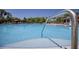 A view of a crystal clear pool, with a handrail leading to the pool, and lounge chairs with umbrellas in the background at 19082 Umberland Pl, Land O Lakes, FL 34638
