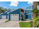 Charming two-story home with a blue exterior, front lawn, and attached one-car garage at 2026 Golfview Dr # 2026, Tarpon Springs, FL 34689