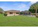 Expansive backyard featuring a screened-in pool, lush green grass, and mature trees, offering a private outdoor retreat at 2122 Meadow Lark Rd, Spring Hill, FL 34608