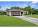 Well-maintained home with a two-car garage, mature landscaping, and a green lawn, providing comfort and style at 2122 Meadow Lark Rd, Spring Hill, FL 34608
