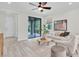 Well-lit living room with light wood tile floors, modern furnishings and sliding glass doors at 3056 Abrams Trl, Odessa, FL 33556