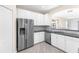 Modern kitchen with stainless steel refrigerator, white cabinets, granite counters, and mosaic backsplash at 3119 Oyster Bayou Way, Clearwater, FL 33759