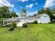 Charming backyard view with a screened-in pool, lush lawn, and a light blue house against a cloudy blue sky at 31726 Sylvian Ln, Dade City, FL 33525