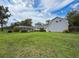 Expansive backyard showcasing the home, storage, screened patio, and lush greenery at 31726 Sylvian Ln, Dade City, FL 33525