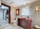 Bright bathroom with travertine walls, soaking tub, and wood vanity; washer/dryer in adjacent laundry at 31726 Sylvian Ln, Dade City, FL 33525