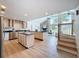 Open kitchen and living area with an island, stainless steel appliances, wood floors, and stone fireplace feature at 31726 Sylvian Ln, Dade City, FL 33525