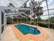 Backyard pool with screen enclosure surrounded by lush landscaping and mature trees at 31726 Sylvian Ln, Dade City, FL 33525
