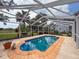 Backyard pool in screened enclosure with brick coping, mature landscaping, and a partial view of the home at 31726 Sylvian Ln, Dade City, FL 33525