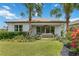 Landscaped backyard with covered patio, tropical trees, colorful plants, and lush green lawn at 3511 Malta Ave, Wesley Chapel, FL 33543