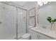 This bathroom features white patterned walls, a glass-door shower, framed art, and modern fixtures at 3511 Malta Ave, Wesley Chapel, FL 33543