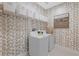 Well-organized laundry room boasts patterned walls, a washer and dryer, and ample storage at 3511 Malta Ave, Wesley Chapel, FL 33543