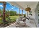 Inviting covered patio features comfortable seating, tropical landscaping, and blue sky views at 3511 Malta Ave, Wesley Chapel, FL 33543