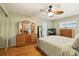 Bedroom with wood laminate floors, ceiling fan, mirrored closet doors, and an entertainment center at 3534 Cockatoo Dr, New Port Richey, FL 34652
