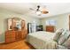Bedroom with wood laminate floors, ceiling fan, mirrored closet doors, and an entertainment center at 3534 Cockatoo Dr, New Port Richey, FL 34652