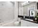 Bathroom featuring patterned wallpaper, black vanity, and marble-tiled shower and backsplash at 3915 Corsica Pl, Wesley Chapel, FL 33543