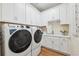 Bright laundry room with modern washer and dryer, ample cabinet space, and stylish gold geometric wallpaper at 3915 Corsica Pl, Wesley Chapel, FL 33543