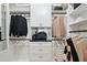 Custom walk-in closet with white shelving units, drawers, hanging rods, and a sleek black countertop at 3915 Corsica Pl, Wesley Chapel, FL 33543