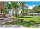 Expansive backyard with large trees, a screened pool, a red shed, a playground, and a glimpse of the lake at 4541 School Rd, Land O Lakes, FL 34638