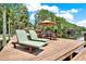Relaxing dock features lounge chairs and an umbrella-covered dining table for lakeside entertainment and leisure at 4541 School Rd, Land O Lakes, FL 34638
