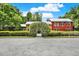 Eye-catching home with yellow and red facade, complemented by a neatly manicured lawn and arched greenery at 4541 School Rd, Land O Lakes, FL 34638