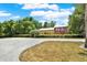 Spacious gravel drive leading to a charming yellow and red home, framed by verdant landscaping at 4541 School Rd, Land O Lakes, FL 34638