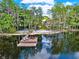 Scenic waterfront view with a dock, beach, and home nestled among towering trees at 4541 School Rd, Land O Lakes, FL 34638