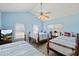 Cozy bedroom with three beds, ceiling fan, light blue walls, and natural light from two windows at 4918 Forecastle Dr, New Port Richey, FL 34652