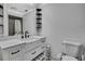 Modern bathroom with white cabinets, vanity, decorative shelves, and a toilet at 5113 Cedar Ln, Brooksville, FL 34601