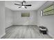 Bedroom with ceiling fan, gray wood floors, and natural light from two windows at 5113 Cedar Ln, Brooksville, FL 34601