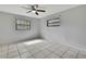 Bedroom with white tile floors, a ceiling fan, and natural light from two windows at 5113 Cedar Ln, Brooksville, FL 34601