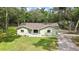 Charming single story home with a light green exterior, spacious front yard, and a backdrop of mature trees at 5113 Cedar Ln, Brooksville, FL 34601