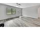Bright living room featuring modern gray wood floors, fan, and large windows at 5113 Cedar Ln, Brooksville, FL 34601