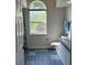 Bathroom with blue-tiled floor, toilet, and large window providing natural light at 5294 Elkin Ave, Spring Hill, FL 34606