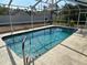 A screened-in swimming pool features clear blue water and accessibility rails for easy and safe enjoyment at 5294 Elkin Ave, Spring Hill, FL 34606
