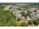 A high, clear aerial shot showing houses and backyards surrounded by green trees, and a distant lake at 6125 Desert Peace Ave, Land O Lakes, FL 34639