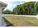 Large, grassy backyard enclosed with a white fence and lush green trees offering privacy at 6125 Desert Peace Ave, Land O Lakes, FL 34639