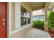 View of front porch with decorative white trim and brick-red front door at 6125 Desert Peace Ave, Land O Lakes, FL 34639