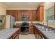 Bright kitchen featuring stainless steel appliances, granite countertops, and dark wood cabinetry at 6125 Desert Peace Ave, Land O Lakes, FL 34639