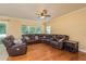 Spacious living room featuring a large leather sectional, ceiling fan, and hardwood floors at 6125 Desert Peace Ave, Land O Lakes, FL 34639