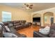 Spacious living room featuring a large leather sectional, ceiling fan, and hardwood floors at 6125 Desert Peace Ave, Land O Lakes, FL 34639