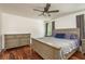 Main bedroom with wood floors, a ceiling fan, and a large bed with an upholstered headboard at 6125 Desert Peace Ave, Land O Lakes, FL 34639