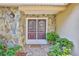 Close-up of the entryway with stylish double doors, stone accents, and lush landscaping around the walkway at 6172 Prestwick Ct, Spring Hill, FL 34606
