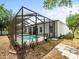 An exterior view of a backyard, complete with pool, screen, and planting area at 6273 Pinehurst Dr, Spring Hill, FL 34606