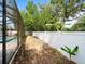 The backyard boasts a screened pool area, a white fence, and various plants at 6273 Pinehurst Dr, Spring Hill, FL 34606