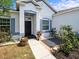 Inviting front porch with a walkway, black door, and colorful landscaping at 6273 Pinehurst Dr, Spring Hill, FL 34606