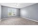 Bedroom features a ceiling fan, neutral carpet and walls, and a bright window at 6440 Curtiss Ln, Spring Hill, FL 34609