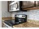 Kitchen featuring granite counters, stainless appliances, mosaic backsplash, and dark wood cabinets at 6440 Curtiss Ln, Spring Hill, FL 34609