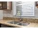 Close-up of a kitchen sink with granite countertops, mosaic backsplash, and dark wood cabinets at 6440 Curtiss Ln, Spring Hill, FL 34609