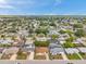 A wide aerial shot shows a neighborhood with tree-lined streets and various single-Gathering homes under a partly cloudy sky at 7035 Cutty Sark Dr, Port Richey, FL 34668